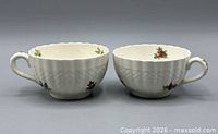Front side view of both teacups showing pattern, basket-weave band and floral decoration