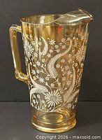 Full view of marigold carnival glass pitcher showing handle, ice lip, floral pattern