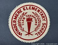 Front view of round patch showing text, torch and laurel graphic
