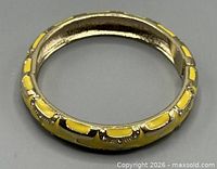 Top view of yellow enamel gold-tone hinged bangle bracelet showing geometric design and rhinestones