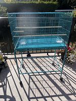 Full view of turquoise bird cage on stand with wheels