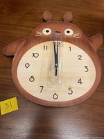 Front view of character-shaped wall clock with plastic hand guard
