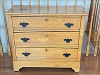 Front view of oak dresser showing three drawers and hardware