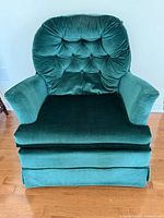 Front view of emerald green tufted velvet armchair with skirted base