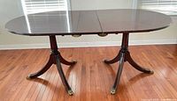 Overall side view of table showing twin pedestals, oval top, brass capped feet