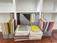Shelves with large quantity of sheet music, books, spiral notebooks and grey magazine holders