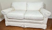 Front view of off-white slipcovered loveseat showing overall design and condition