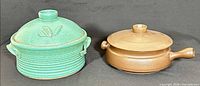 Green and brown covered casserole dishes side by side, lids on