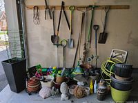 Overall lot showing long-handled tools, hose, planters and decor