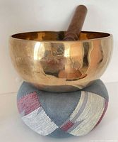 Brass singing bowl on fabric cushion with wooden mallet inside