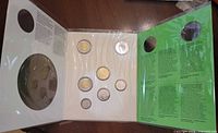 Interior view displaying seven uncirculated coins in plastic holders