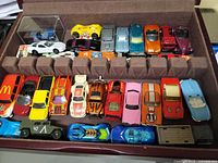 Open wooden case showing two rows of die-cast cars