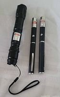 Three laser pointers laid out for size and style reference
