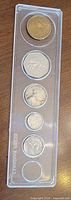 Five coins in clear plastic strip holder