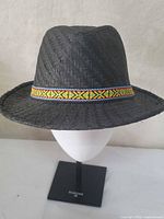 Front view of black straw fedora with multicolour hatband on stand