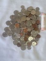 Loose mixed U.S. coins with sealed penny roll on white surface