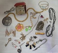 Full layout of jewellery pieces and travel clock on white background