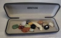 Open Kenneth Cole Reaction case showing all 14 assorted pendants inside