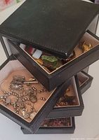 Stacked open drawers showing assorted jewelry pieces inside black case