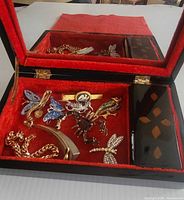 Open box showing red velvet interior, mirror and assorted jewelry pieces