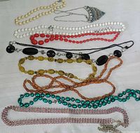 All nine necklaces laid horizontally showing bead types and colors