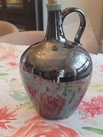 Front view of metallic glazed jug showing ovoid form and handle