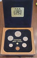 Open case showing seven coins in black tray with gold Canada Official Officielle text