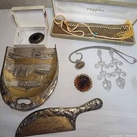 Group shot showing crumb tray, crumber, brooch, pendant, earrings and three necklaces