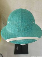 Top and front view of woven teal straw helmet with white brim strip