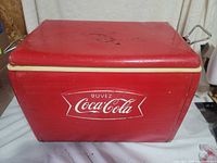 Front view of red Buvez Coca-Cola metal cooler showing logo and handles