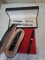 Overview showing Cross box with two chrome instruments and eyeglass case with three blue/black pens