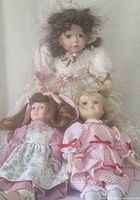 All three dolls seated together showing size comparison and outfits