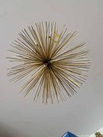 Full view of gold metal starburst showing radiating rods