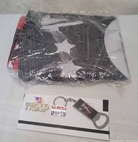 Flag folded in plastic wrap alongside boxed pins and keychain bottle opener