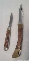 Two folding pocket knives displayed closed and partly open