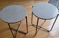 Two matching terrazzo-top tables standing on wood floor