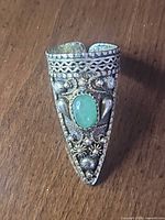Front view of elongated filigree ring showing green cabochon and floral details