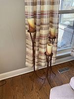 Three graduated height metal candle stands with pillar candles