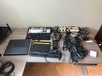 Entire lot showing keyboards, cooling pad, power bar, cables and peripherals on tabletop