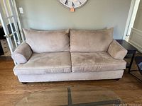 Front view of beige microsuede sofa, shows two seat and back cushions, rolled arms