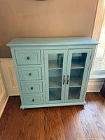 Front view of blue sideboard showing four drawers and dual glass doors