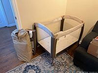 Playard assembled beside carry bag and accessory panel visible