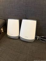 Front view of two Netgear Orbi RBR850 routers on couch