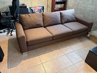 Full view of brown three-seat sofa against wall