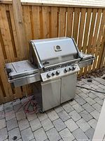 Front angled view of entire stainless steel grill with side shelves and control panel