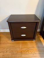 Front view of first nightstand showing drawers, pulls and feet