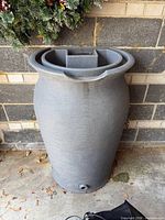 Front view of gray rain barrel showing tapered shape and recessed top opening