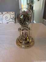 Full view of Rhythm anniversary clock under dome on table