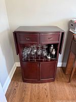 Front view of cabinet with doors open showing drawers, glassware and shaker