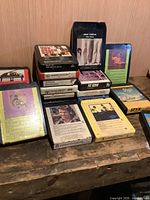 Overall view of two stacks of 8-track tapes showing identifiable titles and cartridge colours.